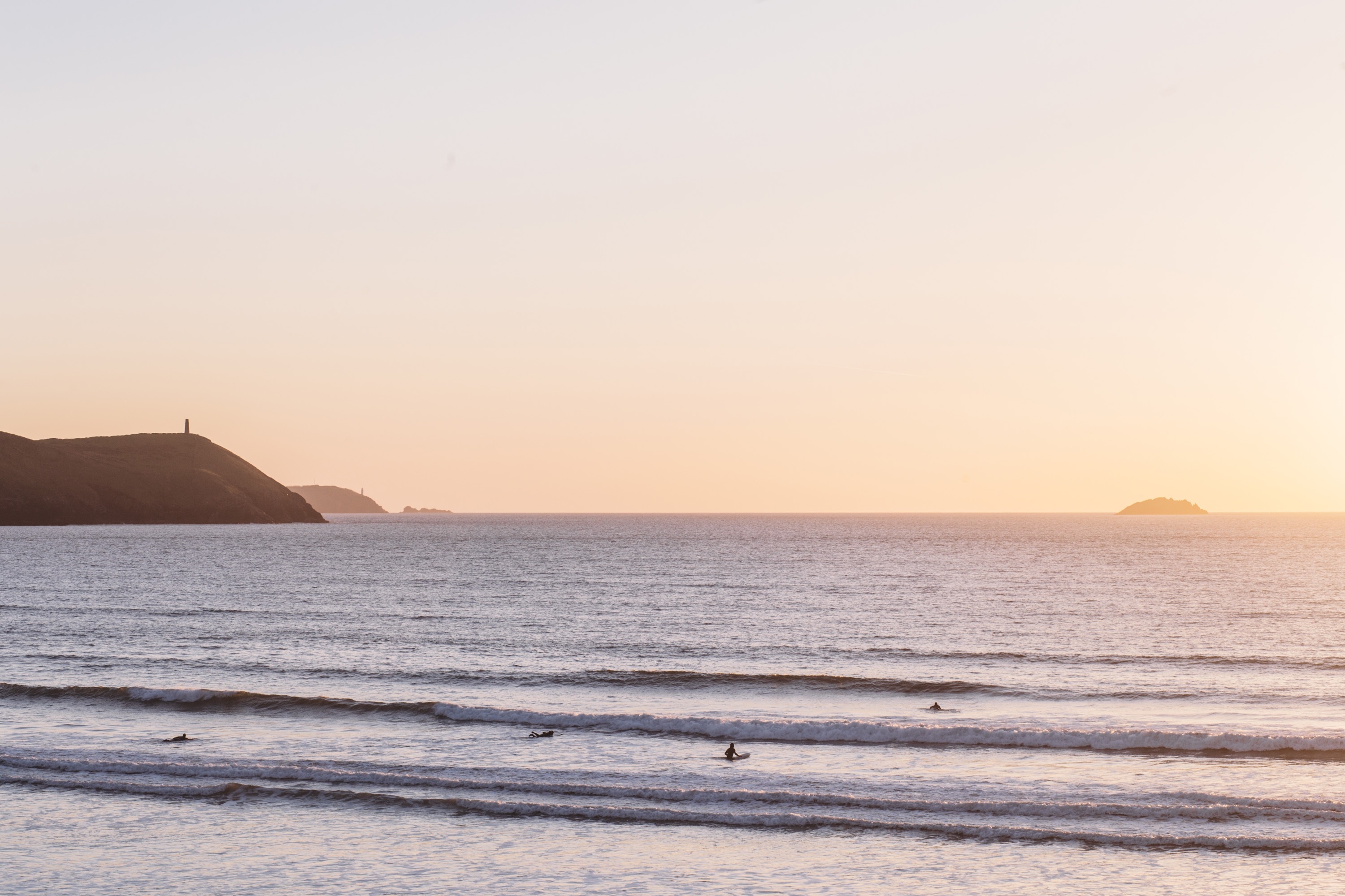 Sunset and surfers at Polzeath Beach