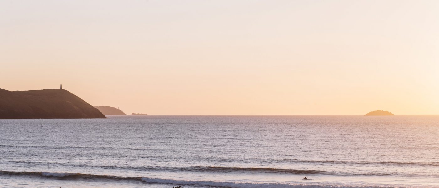 Sunset and surfers at Polzeath Beach